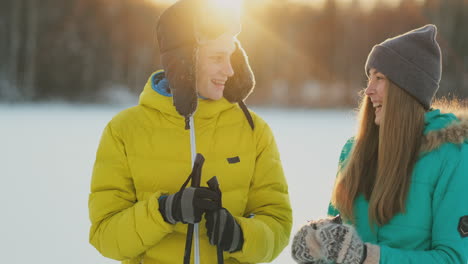 Ein-Mann-In-Einer-Gelben-Jacke-Und-Ein-Mädchen-In-Einem-Blauen-Overall-Fahren-In-Zeitlupe-Bei-Sonnenuntergang-Ski